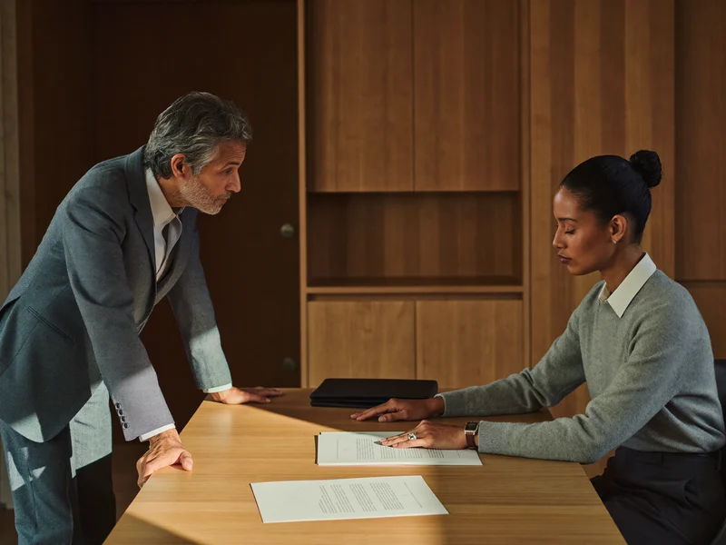Illustration of an adviser listening to a client reviewing papers at a quiet desk